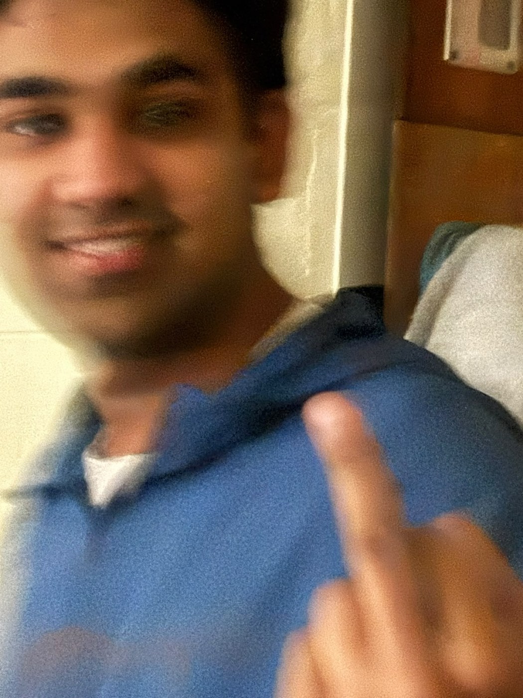 Blurry selfie of Pranav grinning and raising his middle finger