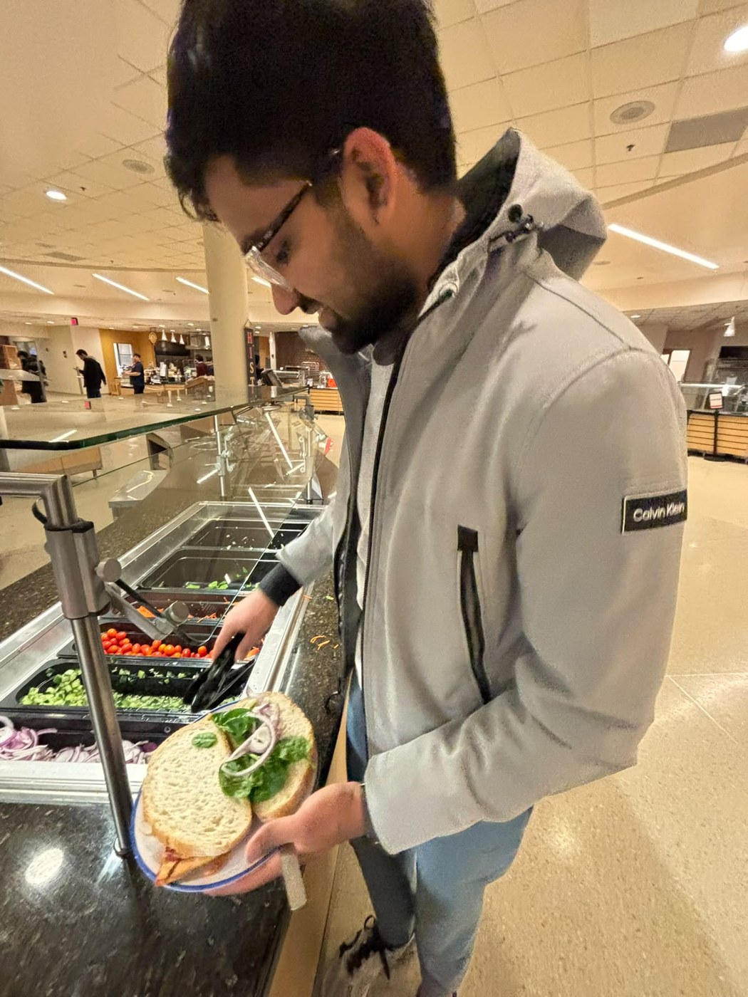 Pranav at the dining hall salad bar assembling a sandwich