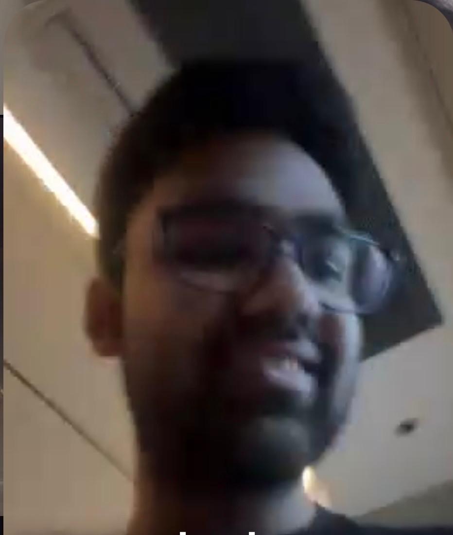 Blurry low-angle video call frame of Pranav grinning